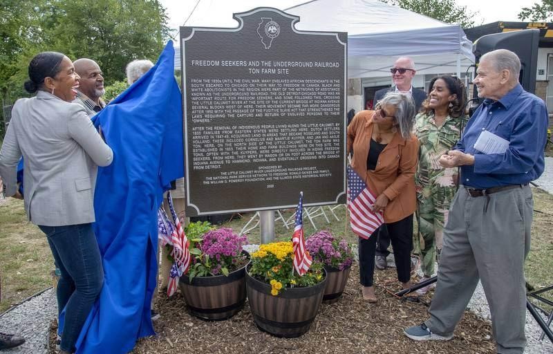dedication of underground railroad site with barrels of flowers in front and people around